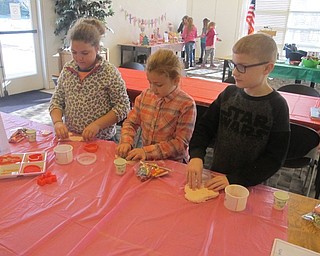 Neighbors | Zack Shively.Jennifer Kuczek made eight stations related to the Nutcracker story and ballet. Pictured, Paige, Sofia and Nathan Becker play with "Sugar Plum Fairy dough" that Kuczek made for the event.