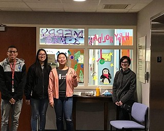 Neighbors | Submitted .Pictured are Boardman art students who painted Holiday themed window panels at Akron’s Children Hospital in Boardman. The students are Raymond Prisby, Tina Zheng, Sandy Li and Cambrie Kasler.