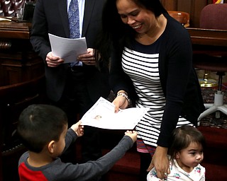 Jeny Wilcoxson receives her citizenship certificate from her son, Brody(4) as she holds her daughter Olivia(2) during a naturalization ceremony, Thursday, Jan. 24, 2018, at the Mahoning County Courthouse in Youngstown...(Nikos Frazier | The Vindicator)