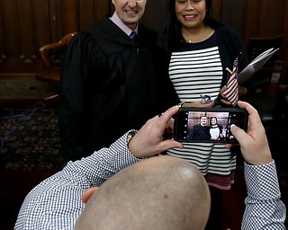 Eric Wilxocson takes a picture of his wife, Jeny and Judge Rusu after she was sworn in as a US Citizen during a naturalization ceremony, Thursday, Jan. 24, 2018, at the Mahoning County Courthouse in Youngstown...(Nikos Frazier | The Vindicator)