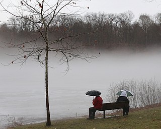 Bob and Judith Stanger of Boardman sit on a bench at Glacier Lake looking at the fog layer created by warm rain interacting with the ice layer on the surface of the lake, Thursday, Jan. 11, 2018, in Mill Creek Park. ..(Nikos Frazier | The Vindicator)