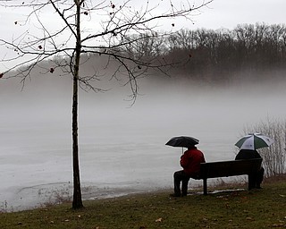 Bob and Judith Stanger of Boardman sit on a bench at Glacier Lake looking at the fog layer created by warm rain interacting with the ice layer on the surface of the lake, Thursday, Jan. 11, 2018, in Mill Creek Park. ..(Nikos Frazier | The Vindicator)