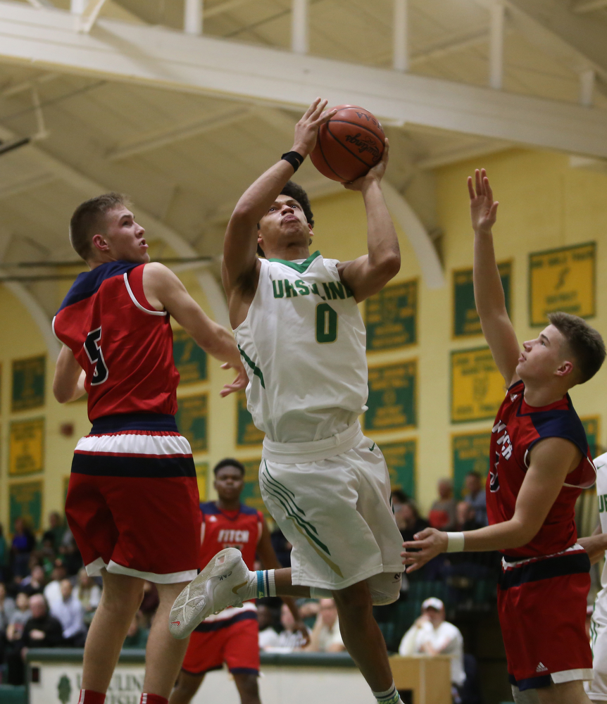 Ursuline forward Devan Keevey (0) goes up for a layup between Austintown Fitch forward Cole Constance (5) and Austintown Fitch guard Blake Baker (3) in the second quarter of an OHSAA high school basketball game, Tuesday, Feb. 13, 2018, in Youngstown. Ursuline won 63-58...(Nikos Frazier | The Vindicator)