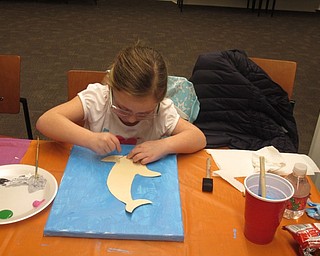 Neighbors | Zack Shively.The library provided the children with all of the materials for the painting, including paints, brushes and a stencil of a dolphin. Pictured, Rylynn Stafford traced the dolphin stencil for her painting.
