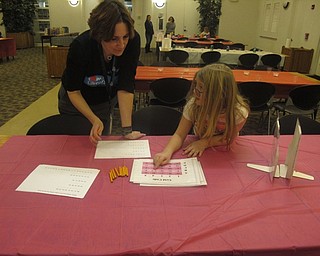 Neighbors | Zack Shively.STEAM stands for science, technology, engineering, arts and mathematics. Librarian Nikki Puhalla set up a station for each component of STEAM. Pictured, she helps an attendee with decoding a secret message.