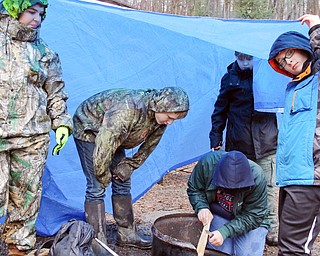 Members of Troop 9080 of North Lima hold a tarp over their fire pit while trying tp make a fire  during the Klondike Gold Rush at Camp Stambaugh on Saturday morning.  Dustin Livesay  |   The Vindicator  2/24/18  Camp Stambaugh