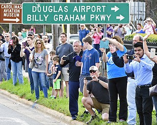 People take photos as the hearse carrying the body of Billy Graham drives toward the Billy Graham Library in Charlotte, N.C., Saturday, Feb. 24, 2018. Graham's body was brought to his hometown of Charlotte on Saturday, Feb. 24, as part of a procession expected to draw crowds of well-wishers. (AP Photo/Kathy Kmonicek, Pool)