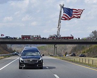 The hearse carrying the body of Billy Graham passes an American flag as it leaves Hickory, N.C., as it drives toward the Billy Graham Library Saturday, Feb. 24, 2018. Graham's body was brought to his hometown of Charlotte on Saturday, Feb. 24, as part of a procession expected to draw crowds of well-wishers. (AP Photo/Kathy Kmonicek, Pool)