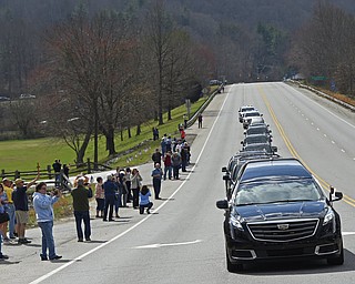People watch as the hearse carrying the body of Billy Graham leaves Asheville, N.C., Saturday, Feb. 24, 2018. Graham's body was brought to his hometown of Charlotte on Saturday, Feb. 24, as part of a procession expected to draw crowds of well-wishers. (AP Photo/Kathy Kmonicek, Pool)