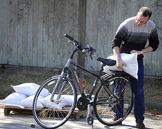 Brian Croteau loads sandbags onto his bike for a short ride back to his Commercial Street home to help secure it as preparations are underway for the approaching storm, Thursday, March 1, 2018 in Provincetown, Mass. Airlines, officials and residents braced Thursday for potentially widespread coastal flooding from a major Nor'easter bearing down on a large swath of the East coast. (Steve Heaslip/The Cape Cod Times via AP)