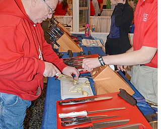 Dennis Tucholski tries out a knive from The Cutco Kitchen as Nate Bratton explains their product at the HBA Home and Garden Show held at Mr. Anthony's in Boardman on Saturday, March 3, 2018...Photo by Scott Williams, The Vindicator.