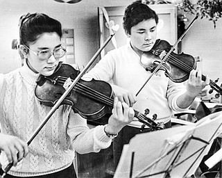 The last rehearsal: Brother and sister duet Maria (12th grade) and Paul (11th grade) Watanakunakorn of Boardman High School practice on their violins Saturday at Canfield High School prior to playing in a music competition sponsored by District V of the Ohio Music Educators Association.  More than 1,200 high school students participated in competitions at both Canfield and Frank Ohl Middle School, Austintown. ..This photo first ran in The Vindicator on Sunday, February 8, 1987...Photo by William D. Lewis, The Vindicator.