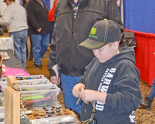 Adam Yarian, age 9, tinkers with some outdoor hunting gear as his grandfather Carl Buhn, both of New Waterford, Ohio, watches at The Sportsman's Hunting and Fishing Supershow and Sale at the Metroplex Expo Center in Girard, Ohio on Sunday March 4, 2018. ..Photo by Scott Williams - The Vindicator.