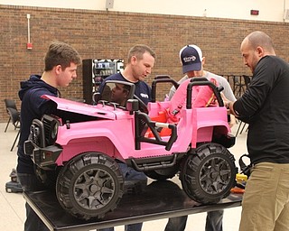Team Addison, from left, Jake Hockensmith, Tom Hopkinson, Eric Pavlicko and Angelo LaMarca, worked to modify a car for Addison to be able to drive at the Go Baby Go build at the Mahoning County Career and Technical Center on Feb. 24.