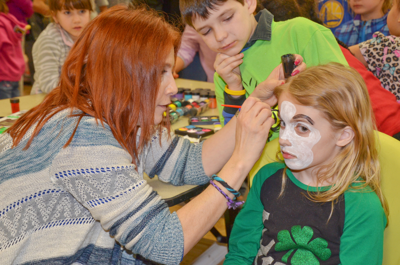 Maria Rosensteel, a 7th grade teacher at Campbell, paints a face on Abby Lencyk, 2nd grade student at South Range, as Oliver Ruediger, 2nd grade student at Campbell, waits his turn at Campbell Community Night at Campbell K-7 School on Thursday, March 15, 2018...Photo by Scott Williams - The Vindicator.