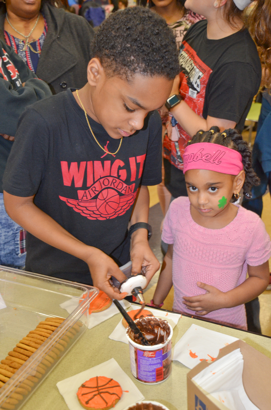 Jabari Rushton, left; 7th grade, helps his sister Serenity Cunningham, right; kindergarten, decorate some basketball cookies at Campbell Community Night at Campbell K-7 School on Thursday, March 15, 2018...Photo by Scott Williams - The Vindicator.