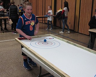 Neighbors | Zack Shively.The PTO gave the Mother Son Night an Olympic theme. To match the theme, they set up a number of games in the gymnasium. Pictured, Kolt Arnold competed in tabletop curling.