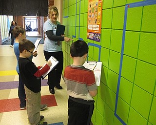 Neighbors | Zack Shively.Teachers throughout the school taught different math lessons in the hallways to have fun, engaging math instruction on Math Day. Pictured, Michelle Battaglia taught students Ethan, Nicky and Tyler about perimeter and area using shapes on the wall.