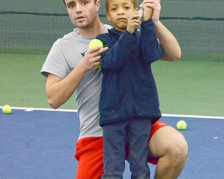 Pol Virgili Blanco, YSU sophomore international business major from Spain, coaches Sergio Shaw, a kindergarten student from Youngstown Community School, on how to swing a tennis racket at the Boardman Tennis Center on March 23, 2018.  

Photo by Scott Williams - The Vindicator 