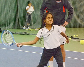 Mercedes Haskins, age 10; from Youngstown Community School, whacks a tennis ball as Vasileios Vardakis, YSU freshman business major from Greece, observes at the Boardman Tennis Center on March 23, 2018.  

Photo by Scott Williams - The Vindicator
