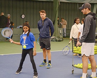 Ce'Ona Green, from Youngstown Community School, age 11, swings at a tennis ball as Thomas De Negri, YSU freshman business major from France, center, and Vasileios Vardakis, YSU freshman business major from Greece, observe at Boardman Tennis Center on March 23, 2018.

Photo by Scott Williams - The Vindicator.