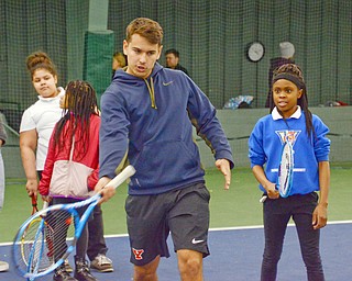 Thomas De Negri, YSU freshman business major from France, instructs Ce'Ona Green, from Youngstown Community School, age 11, on how to properly swing a tennis racket at Boardman Tennis Center on March 23, 2018. 

Photo by Scott Williams - The Vindicator