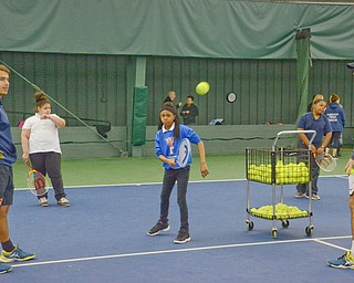 Ce'Ona Green, from Youngstown Community School, age 11, swings at a tennis ball as Thomas De Negri, YSU freshman business major from France, left, and Vasileios Vardakis, YSU freshman business major from Greece, right, observe at Boardman Tennis Center on March 23, 2018.

Photo by Scott Williams - The Vindicator.