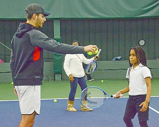 Vasileios Vardakis, YSU freshman business major from Greece, readies a ball for Mercedes Haskins, age 10; from Youngstown Community School, at the Boardman Tennis Center on March 23, 2018.  

Photo by Scott Williams - The Vindicator.