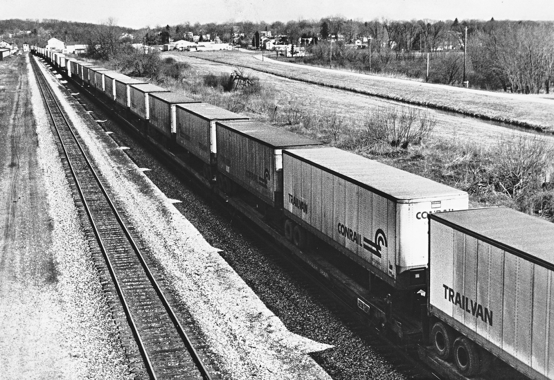 THE LONG HAUL - Consolidated Rail Corp. (Conrail), formed by the government from the old Penn Central and five other bankrupt carries, recorded a record profit of $97.2 million in the second quarter, after posting similar black ink in all of 1982 and 1981.  A key factor in boosting Conrail and the rail industry's resurgence is the continuing growth of so-called "piggyback" travel, under which railroad flatcars carry already-packed containers. Aug. 14-83..ON THE (RAIL)ROAD AGAIN - Perhaps a sign of an economic turnaround, a long line of loaded Conrail Trailvans head west past Leetonia, which can be seen in the background...Photo taken April 4, 1983...Photo by Edward A. Shuba - The Vindicator.