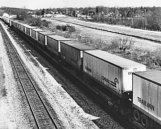 THE LONG HAUL - Consolidated Rail Corp. (Conrail), formed by the government from the old Penn Central and five other bankrupt carries, recorded a record profit of $97.2 million in the second quarter, after posting similar black ink in all of 1982 and 1981.  A key factor in boosting Conrail and the rail industry's resurgence is the continuing growth of so-called "piggyback" travel, under which railroad flatcars carry already-packed containers. Aug. 14-83..ON THE (RAIL)ROAD AGAIN - Perhaps a sign of an economic turnaround, a long line of loaded Conrail Trailvans head west past Leetonia, which can be seen in the background...Photo taken April 4, 1983...Photo by Edward A. Shuba - The Vindicator.