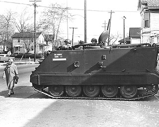 A woman walks nonchainantly by an armoured personnel carrier, one of two that were pressed into service by the National Guard last night.  People emerged from their homes to view the destruction this morning and paid little attention to the guardsmen.