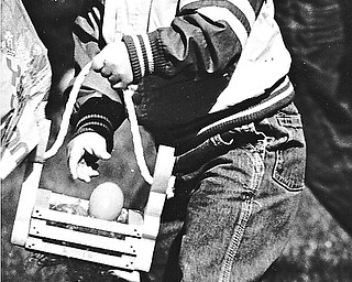FOUND ONE: Two-year-old Zachary Albright, a son of Roy and Jane Albright of Niles, stashed an Easter egg into his wooden basket during an Easter egg hunt Saturday at the First United Methodist Church in Niles...Photo by Robert K. Yosay - The Vindicator