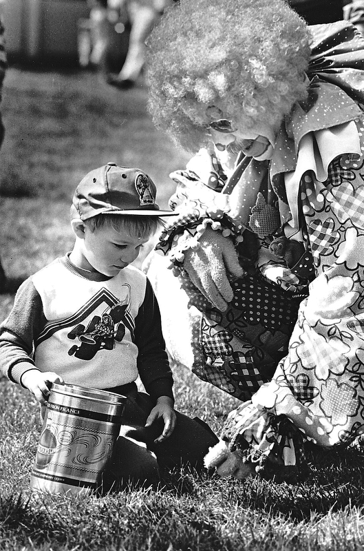 BOYS GET GOODIES DAY EARLY Ð The long-awaited day has finally arrived with area children waking to find Easter baskets filled with chocolate eggs and bunnies and maybe even a jelly bean or two.  David Pavlich, 3, the son of Mr. and Mrs. Milan Pavlich didn't wait until today to begin the fun either.  "Applejack," an Aut Mori Grotto Clown helped David find some goodies at Saturday's Austin Woods Easter egg hunt.  When "Applejack" isn't adorned with his curly wig and jumpsuit, he's better known as Jack Hargate.  "Applejack" lent a hand to many of the eager hunters...Photo by William D. Lewis - The Vindicator