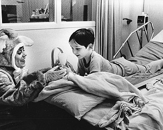 CHILDREN IN HOSPITAL GET HOLIDAY VISITOR:  Nancy Banko, an employee of Ashley Place Nursing Home, became the Easter Bunny on Monday to visit Michael Edwards, 6, a patient at Tod Children's Hospital.  Nursing home residents and employees have made Easter baskets that are being delivered to patients at the hospital.

Photo taken April 13, 1987.

Photo by Robert DeMay - The Vindicator