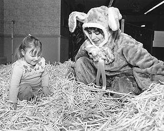 BUNNY IN A BASKET - The Easter Bunny, Nancy Banko (right) of Austintown, and four-year-old Angel Miller of Youngstown, waded through straw in search of Easter eggs at the Ashley Place Health Care Center on Saturday.  Children ages 3 through 7 participated in this year's Easter egg hunt.  

Photo taken March 22, 1986.  

Photo by Patricia L. Fife - The Vindicator.