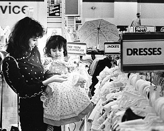 EASTER FASHIONS: New spring bonnets and dresses are always a part of Easter Sunday.  Lorilee Amedia of Youngstown prepared her 1.5-year-old daughter, Michal, for her second Easter celebration Saturday by shopping at the Hills Department Store in the Liberty Plaza.

Photo by William D. Lewis - The Vindicator