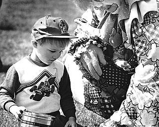 BOYS GET GOODIES DAY EARLY - The long-awaited day has finally arrived with area children waking to find Easter baskets filled with chocolate eggs and bunnies and maybe even a jelly bean or two.  David Pavlich, 3, the son of Mr. and Mrs. Milan Pavlich didn't wait until today to begin the fun either.  "Applejack," an Aut Mori Grotto Clown helped David find some goodies at Saturday's Austin Woods Easter egg hunt.  When "Applejack" isn't adorned with his curly wig and jumpsuit, he's better known as Jack Hargate.  "Applejack" lent a hand to many of the eager hunters.

Photo by William D. Lewis - The Vindicator