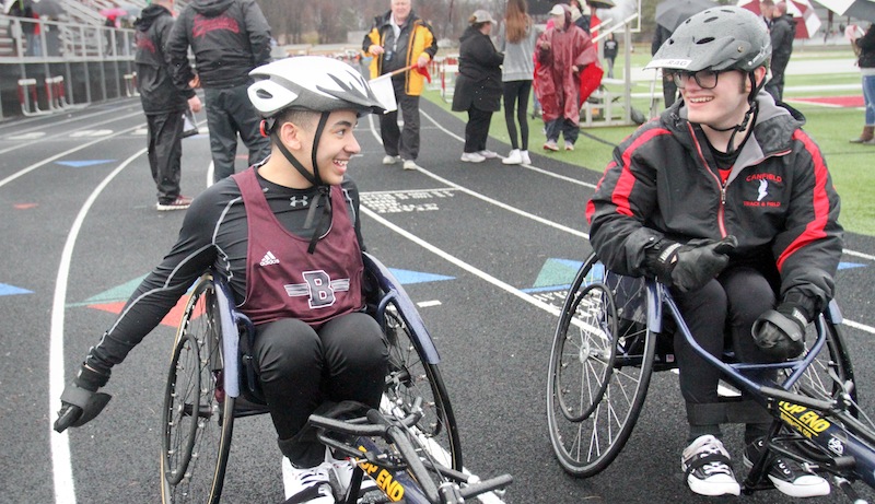 Seated athletes Micah Beckwith, left, of Boardman and Jake Hostetter of Canfield share a moment at the finish of the 100-meter dash on Tuesday at Boardman. Beckwith won the event with a time of 30.2 seconds.