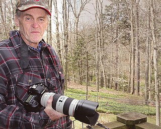 Bob Coggeshall, with the camera he used to take pictures of a raccoon in his yard, one of several in the city over the weekend that appeared sick. Coggeshall said the raccoon was very aggressive during the daylight hours toward him and his dogs.