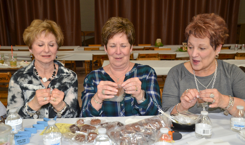 Three friends from Struthers, from left to right, Sandy Beckwith, Judy Davenport, and Judy Takach, race one other to see who can open their sample chocolate from Giannios Candy first at the annual "Taste of Struthers" event held at St. Nicholas in Struthers on Thursday April 12, 2018.

Photo by Scott Williams - The Vindicator