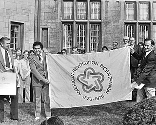 BICENTENNIAL UNIVERSITY - Youngstown State University officially became a bicentennial university this morning as Ohio Sen. Harry Meshel, D-33, center, presented an official Bicentennial flag and certificate to YSU President John Coffelt, left, and Dr. Robert Smith, right.  The brief ceremony gave U.S. Bicentennial Committee sanction to the university's planned festivities to help mark America's 200th birthday.  Dr. Smith, assistant dean of the College of Arts & Sciences, is chairman of YSU's bicentennial committee.

Photo published August 12, 1975