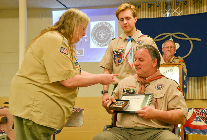 Beth Harnishfeger, left, presents John Russell, seated, with the District Award of Merit at the Whispering Pines Boy Scouts Recognition Dinner at St. James Episcopal Church in Boardman on Sunday, April 15, 2018.  Russell's son, Colin, watches on in approval. The award is available to registered Scouters who render service of an outstanding nature at the district level.

Photo by Scott Williams - The Vindicator