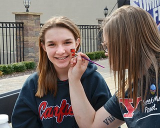 Jordyn Aho, a YSU criminal justice major, (right) paints a YSU "Y" on the face of Mia Lazazzera, 11, from Canfield, at the Federal Frenzy Music and Arts Festival on West Federal Street in downtown Youngstown on Saturday, April 21, 2018.   Mia attended the event with her father Mike and ten-year-old sister Carlie.  

Photo by Scott R. Williams - The Vindicator