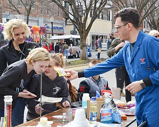Salam Pickard, a YSU chemistry student, performs an experiment for Olivia Loftus, 12, (left) Alexandra Loftus, 8, (right), and mother Jennifer Loftus of Poland at the Federal Frenzy Music and Arts Festival on West Federal Street in downtown Youngstown on Saturday, April 21, 2018.  

Photo by Scott R. Williams - The Vindicator