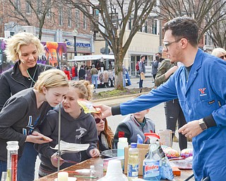 Salam Pickard, a YSU chemistry student, performs an experiment for Olivia Loftus, 12, (left) Alexandra Loftus, 8, (right), and mother Jennifer Loftus of Poland at the Federal Frenzy Music and Arts Festival on West Federal Street in downtown Youngstown on Saturday, April 21, 2018. 

 Photo by Scott R. Williams - The Vindicator .