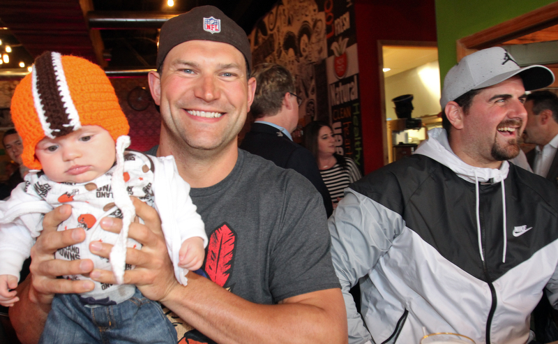William D. Lewis The Vindicator Haden Holmes, 13 weeks, meets former Browns player Joe Thomas, at left  NFL star John Greco during draft night event at Suzies Dogs and Drafts in Boardman. Haden is a son of Matt and Samantha Holmes of Austintown.
