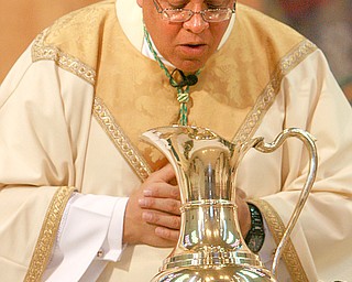 FILE PHOTO: Bishop George Murry breathes over the opening of he chrism vessel as he Blessed the oils. Photo taken April 5, 2007. Photo by Robert K. Yosay - The Vindicator