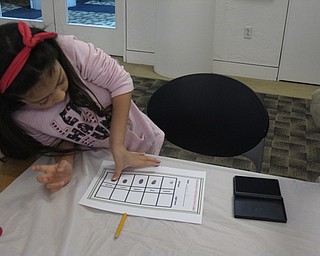 Neighbors | Zack Shively.Austintown librarian Nikki Puhalla organized the "Detectives Wanted" program for children. She gave them the opportunity to check out different mystery books for children and offered a number of fun activities to them. Pictured, Shaylee Nolan stamped her fingerprints on a sheet.
