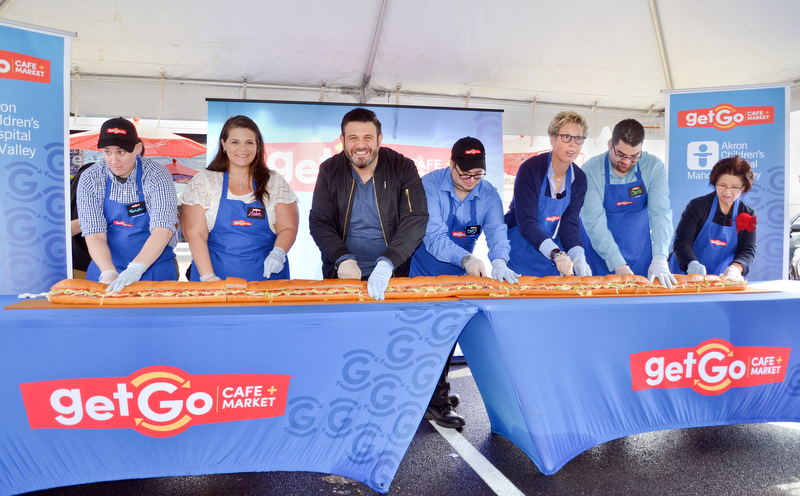The ribbon is cut, or in this case, a gigantic sub sandwich is cut at the grand-opening ceremony of the new GetGo gas station/cafe/market at 133 Boardman-Poland Road in Boardman on Thursday May 3, 2018.   From left to right, there is Rochelle Lawrence, Lelah Hogan, Adam Richman - celebrity chef, Craig Rotz, Polly Flinn - GetGo senior vice president and general manager, Chris Wolfe, and Sharon Hrina - Akron Children's Hospital. 

Photo by Scott Williams - The Vindicator
