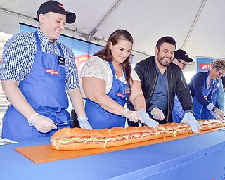 The ribbon is cut, or in this case, a gigantic sub sandwich is cut at the grand-opening ceremony of the new GetGo gas station/cafe/market at 133 Boardman-Poland Road in Boardman on Thursday May 3, 2018.   From left to right, there is Rochelle Lawrence, Lelah Hogan, Adam Richman - celebrity chef, Craig Rotz, Polly Flinn - GetGo senior vice president and general manager, Chris Wolfe, and Sharon Hrina - Akron Children's Hospital. 

Photo by Scott Williams - The Vindicator